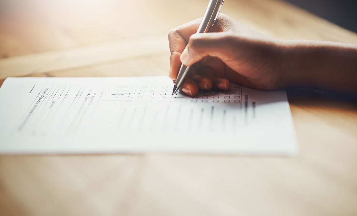 person completing a form with a pen