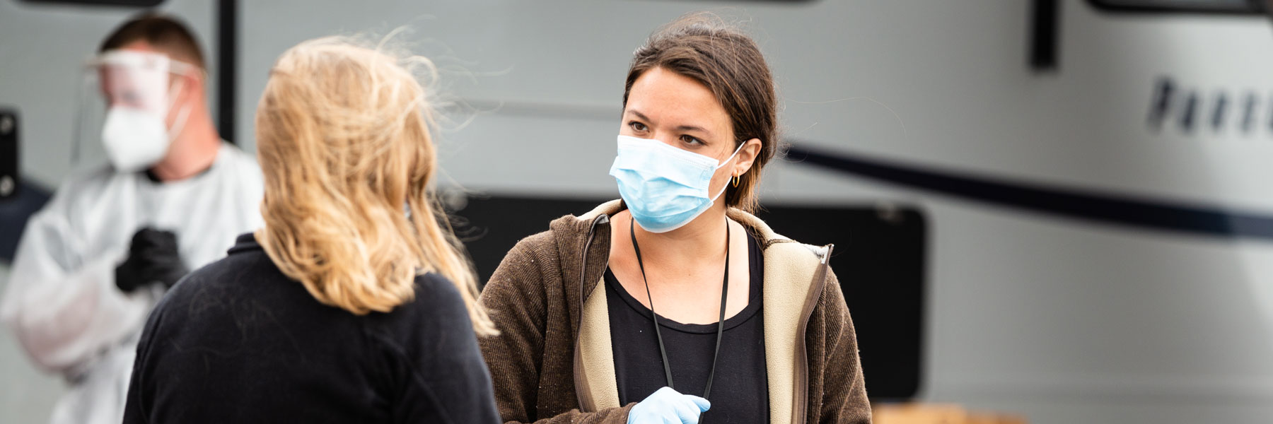 volunteer at clinic wearing mask speaking to patient