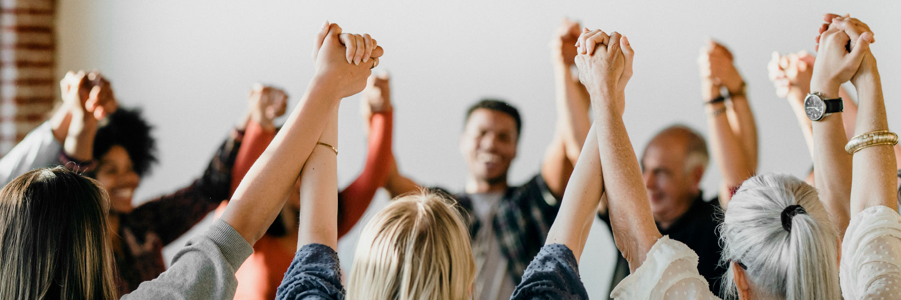 people in circle holding hands up in the air